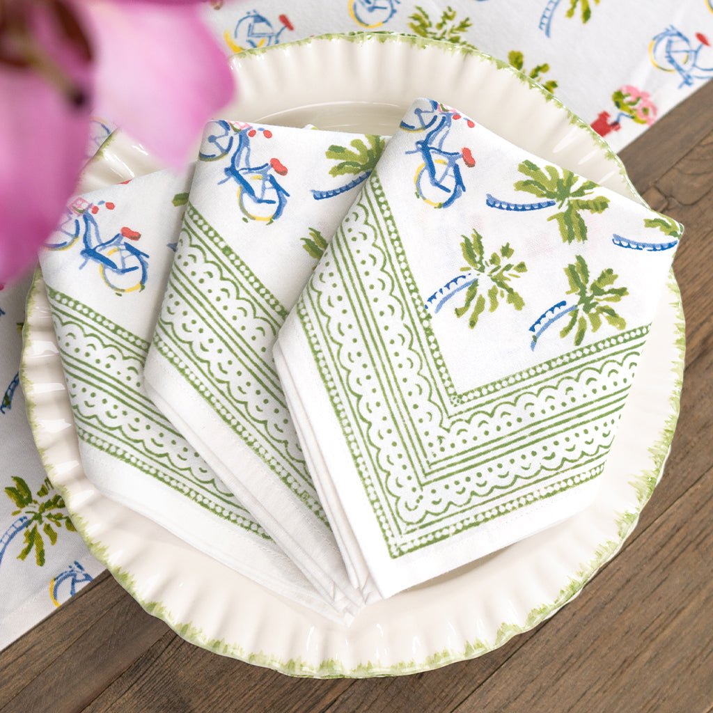 Set of patterned napkins on a wooden table with a floral tablecloth.