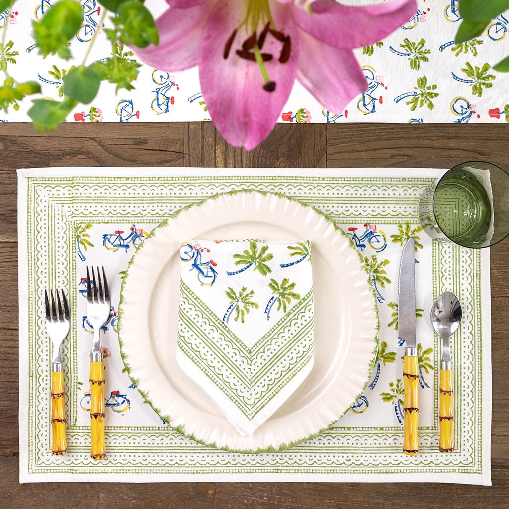 Table setting with a decorative placemat, plate, and cutlery on a wooden table.