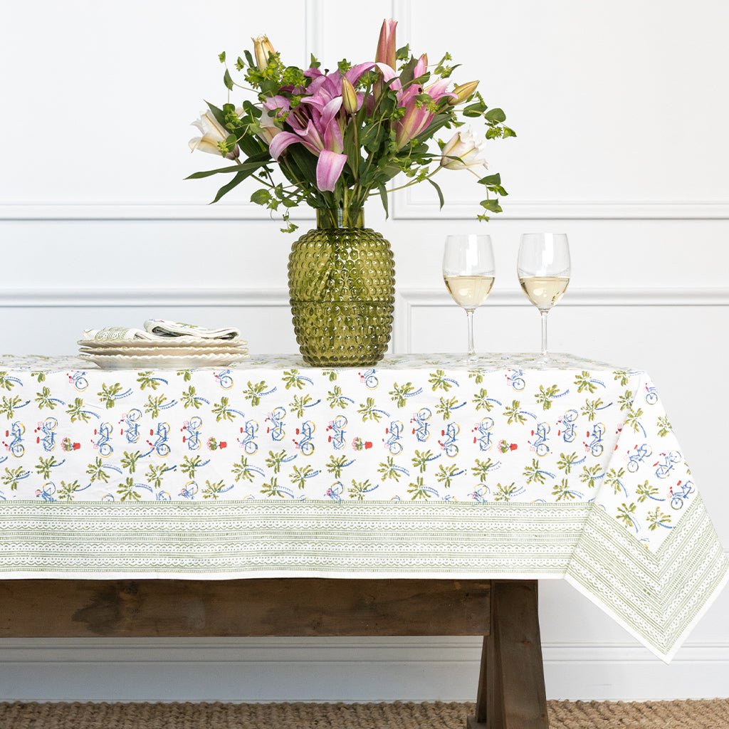 Table setting with floral arrangement, tablecloth, and glasses on a white background