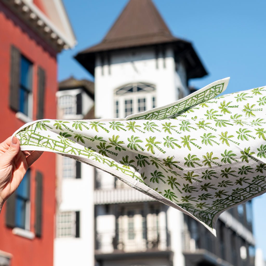 Person holding a green and white patterned napkin in front of a building