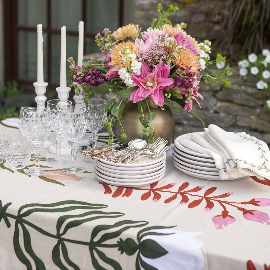 Elegant table setting with floral centerpiece, plates, and cutlery on a decorative tablecloth.