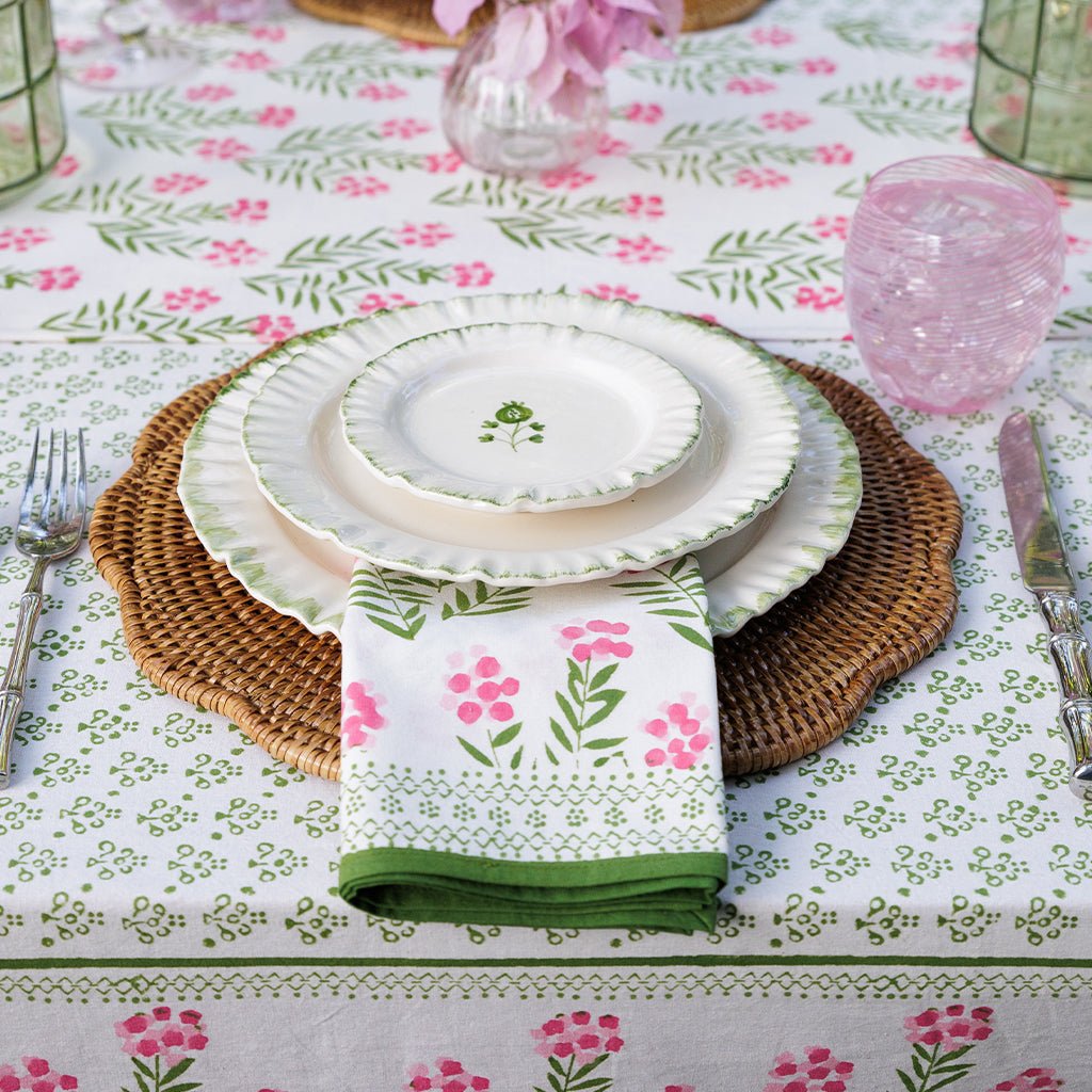 Table setting with floral tablecloth, plates, and napkin on a decorative table.