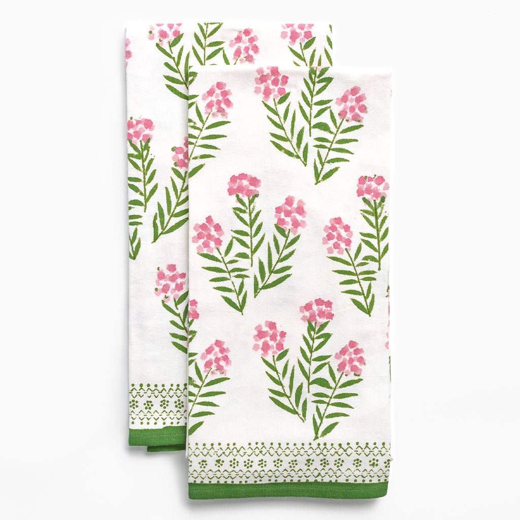 Floral patterned towel with pink flowers and green leaves on a white background