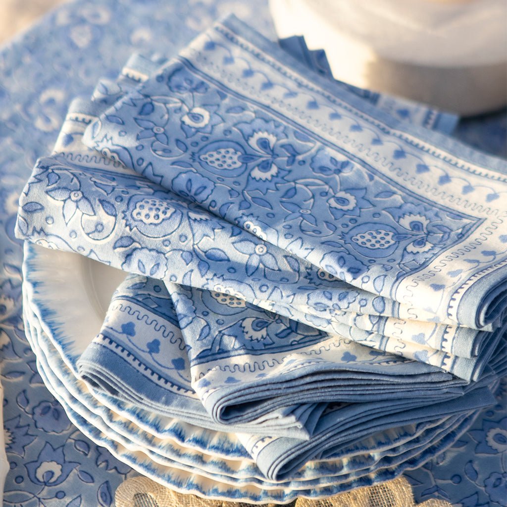 Stack of blue patterned plates and napkins on a matching tablecloth.