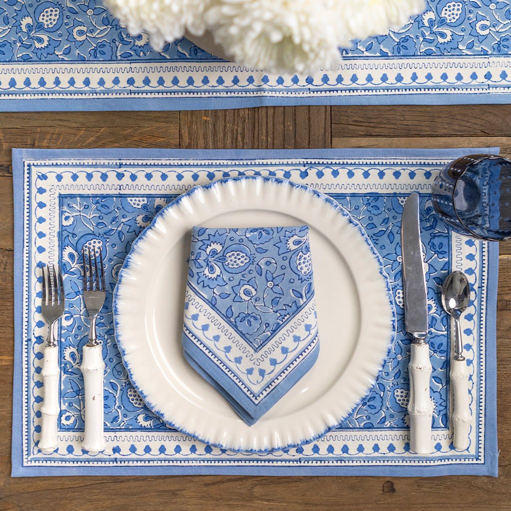 Table setting with blue and white patterned placemat, plate, napkin, and cutlery.