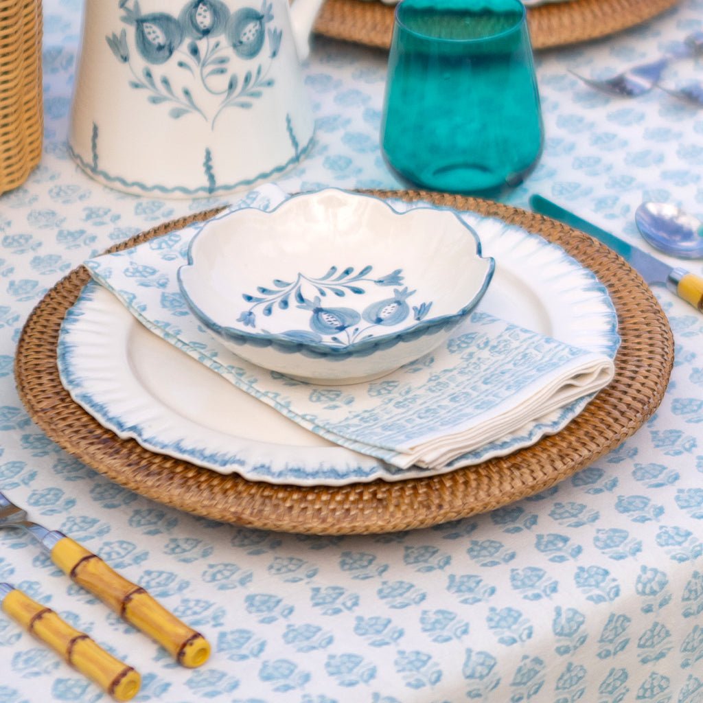 Table setting with blue and white floral patterns on plates, bowls, and tablecloth.