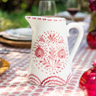 White ceramic pitcher with rose floral patterns on a tablecloth with similar design