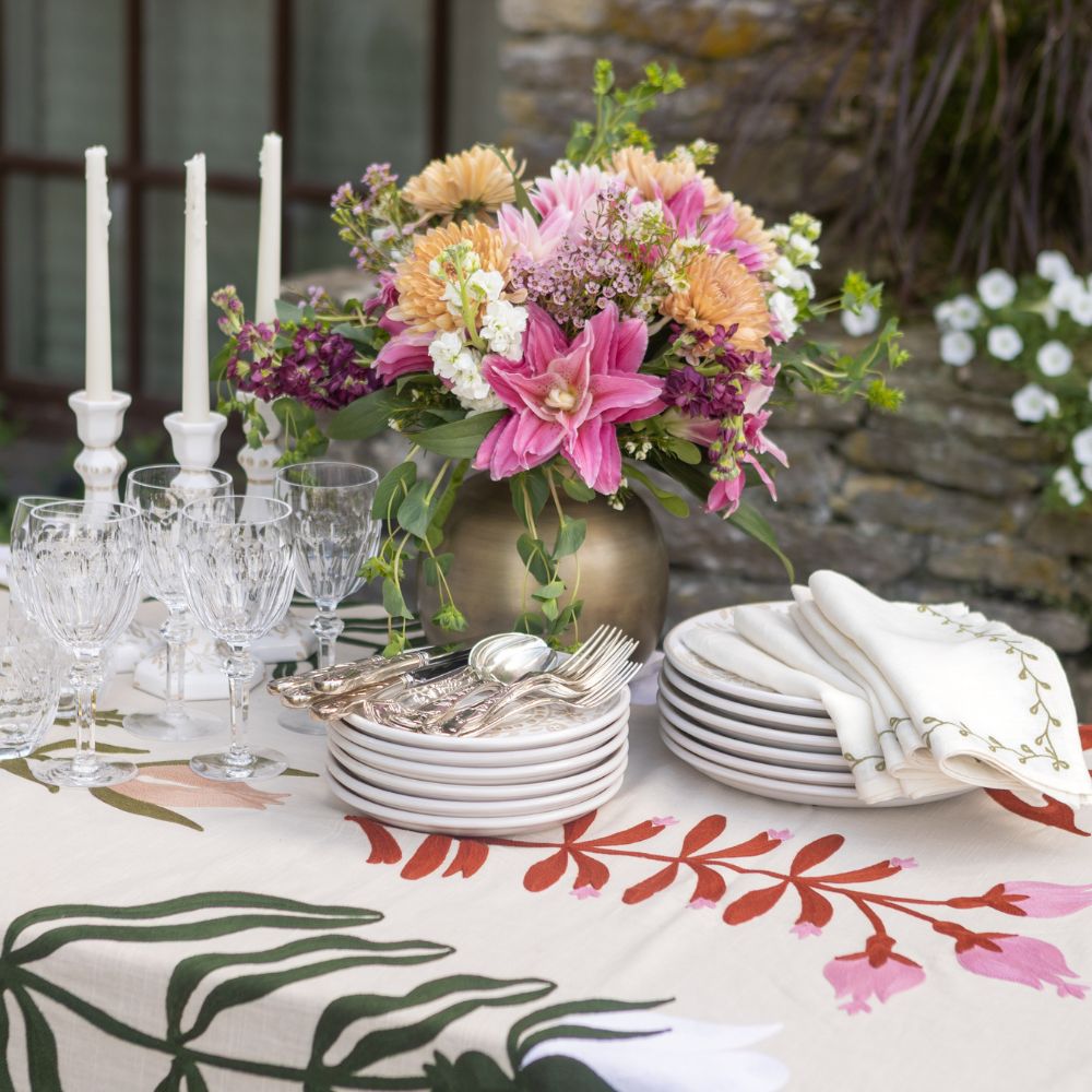 Decorated table with floral centerpiece, plates, and cutlery on a patterned tablecloth.