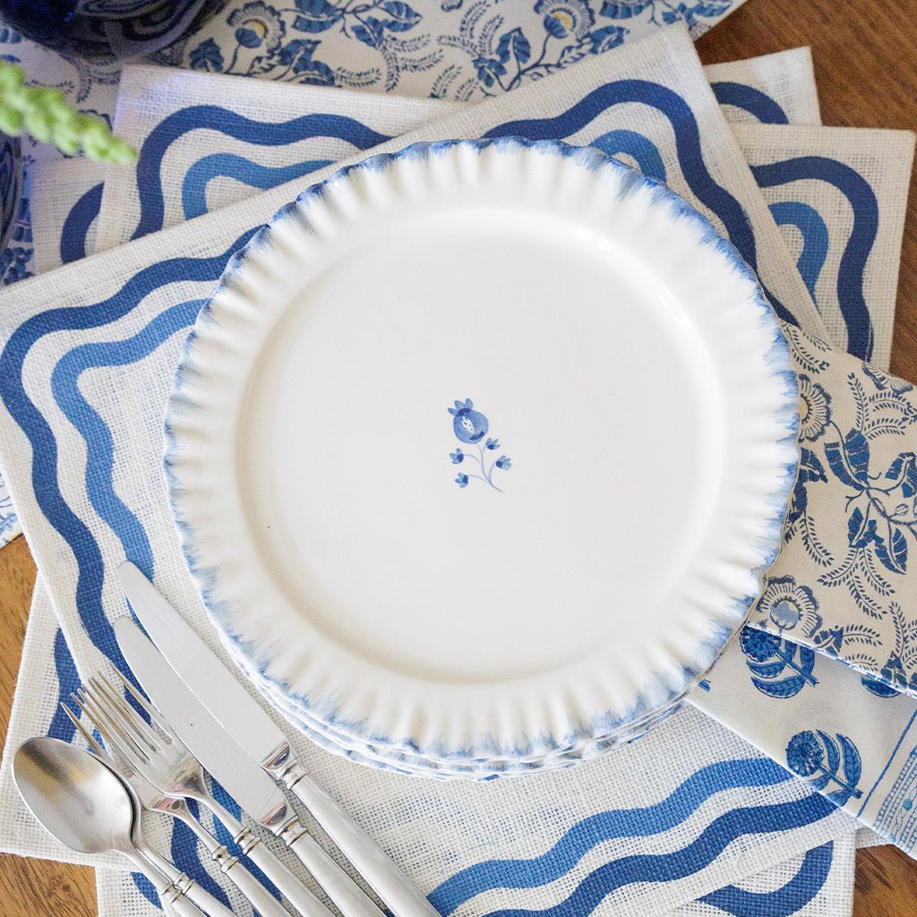White plate with blue patterns on a matching tablecloth with cutlery.