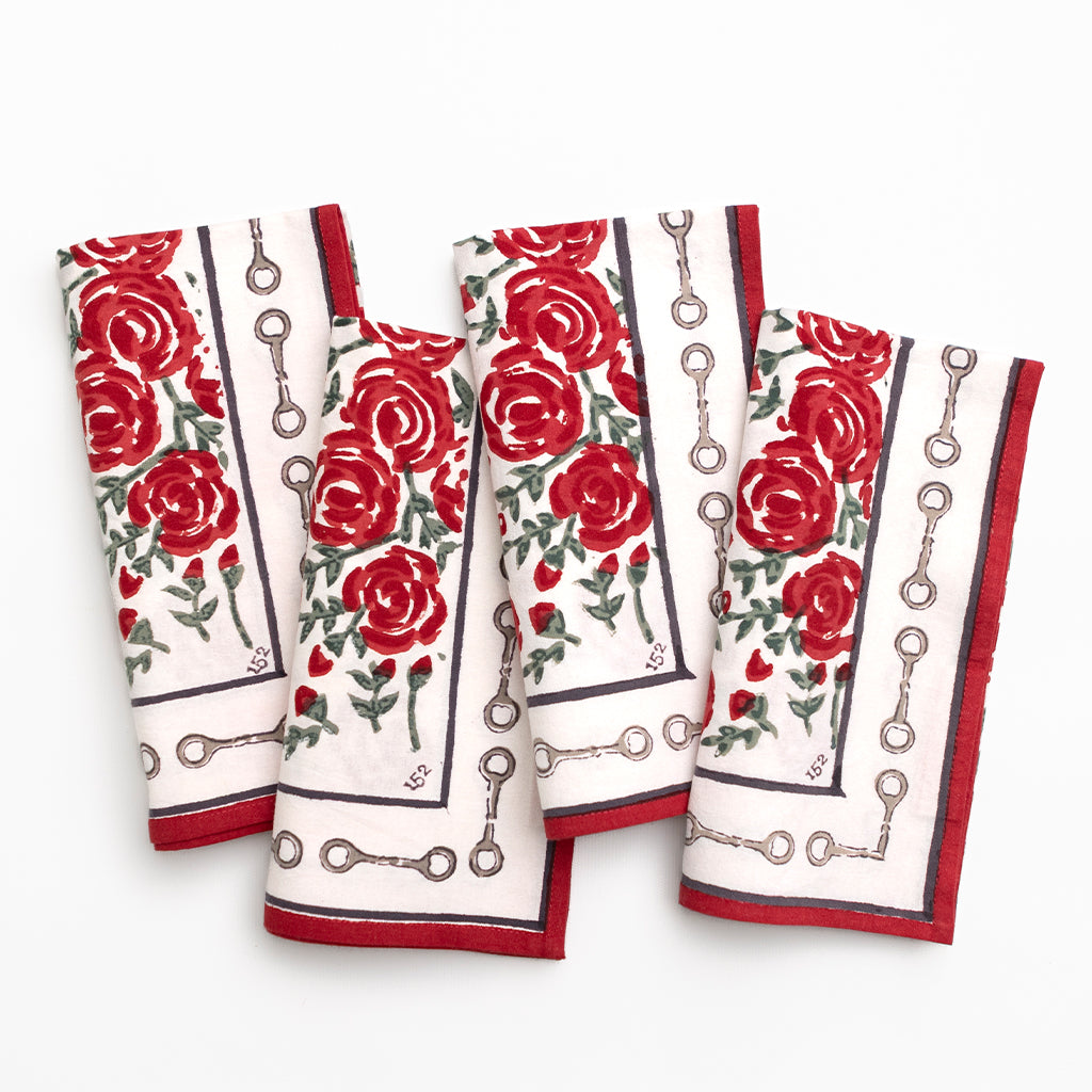 Set of four decorative napkins with a red rose pattern and snaffle bit border on a white background.