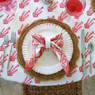 A folded Sagar red and white napkin with a hand block-printed design, displayed on a white plate