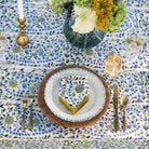 Elegant table setting with floral tablecloth, plates, cutlery, and napkin.