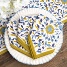 Set of floral-patterned paper plates and napkins on a wooden surface