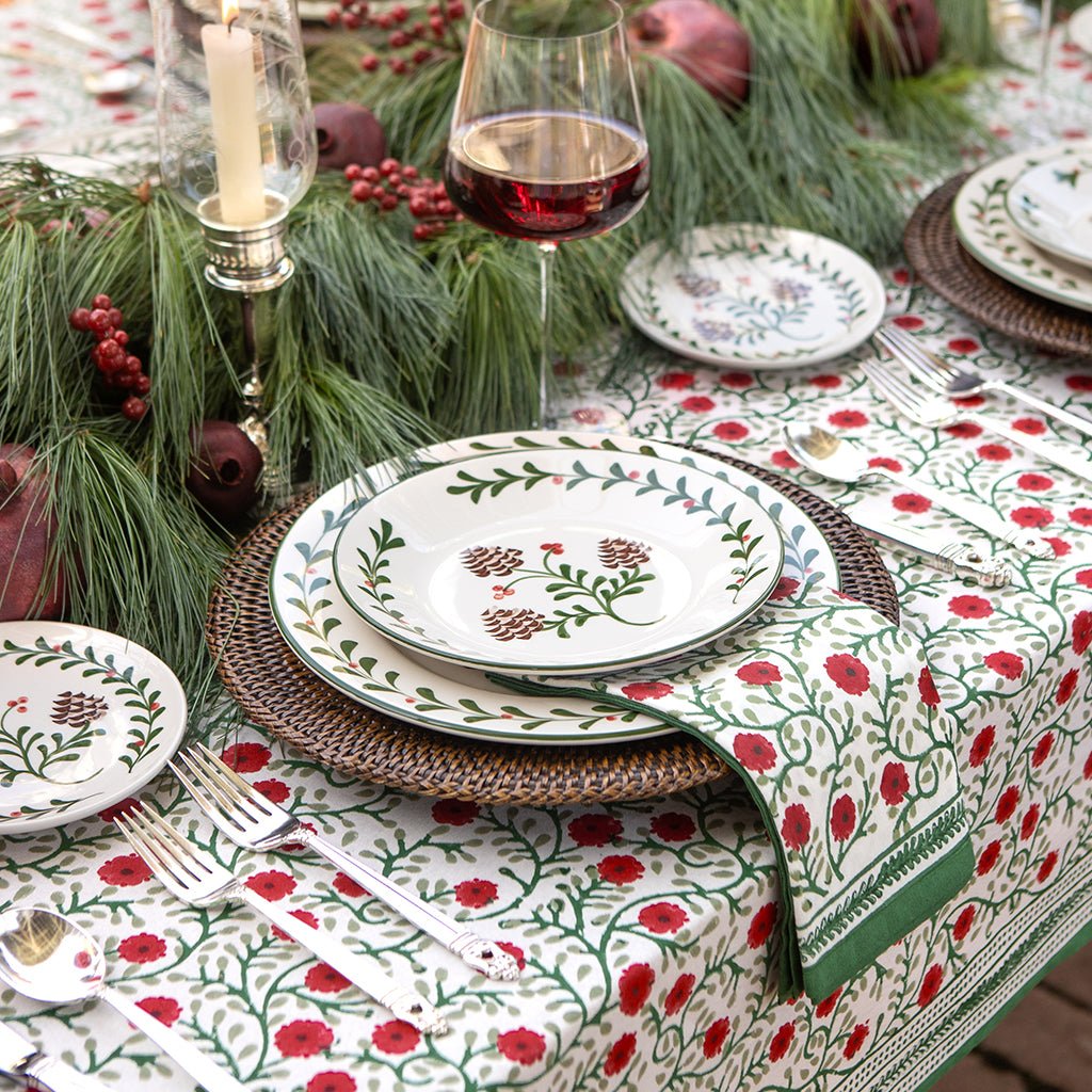 Decorative table setting with floral tablecloth, plates, and glasses.