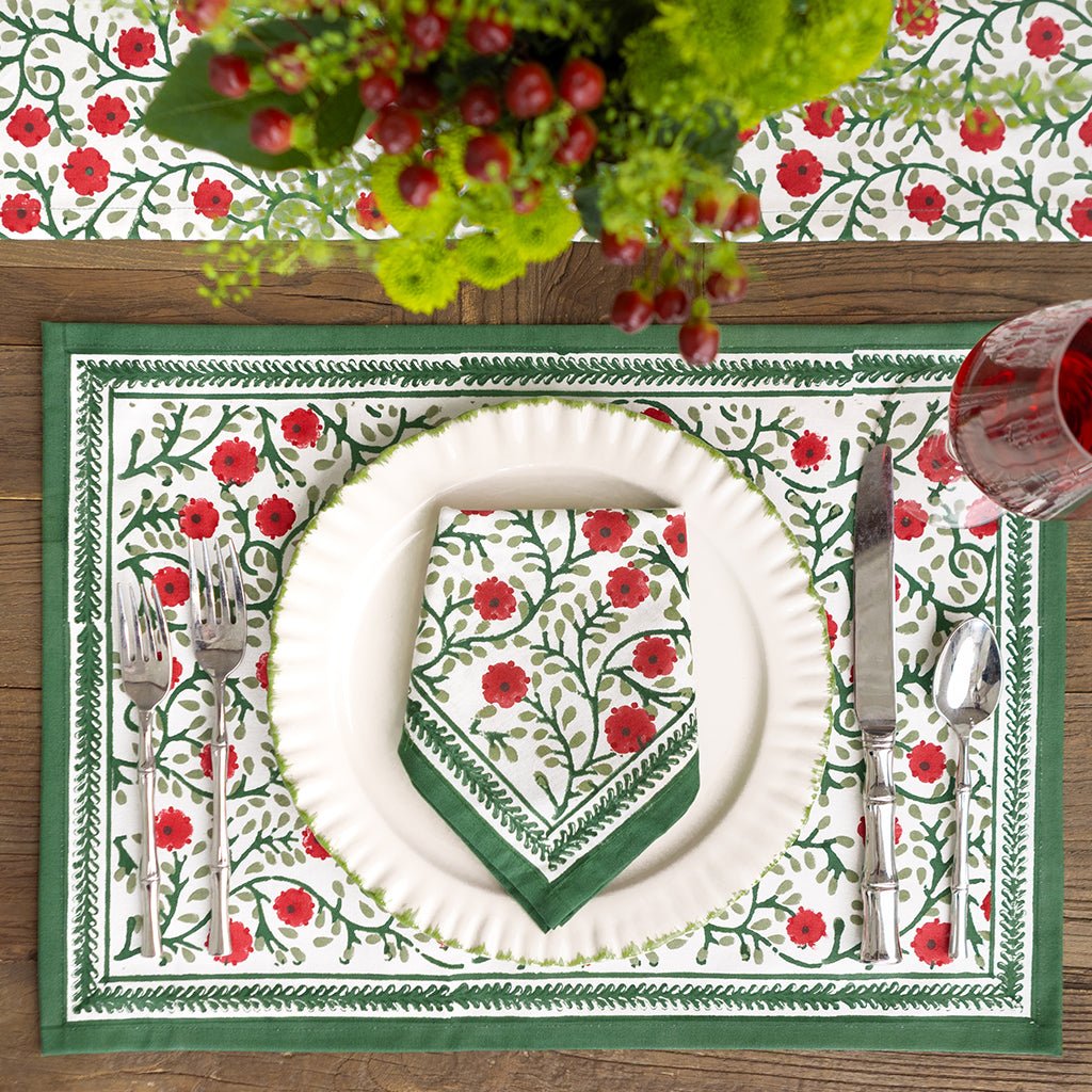 Dining table setting with floral placemat, plate, and cutlery on a wooden surface.