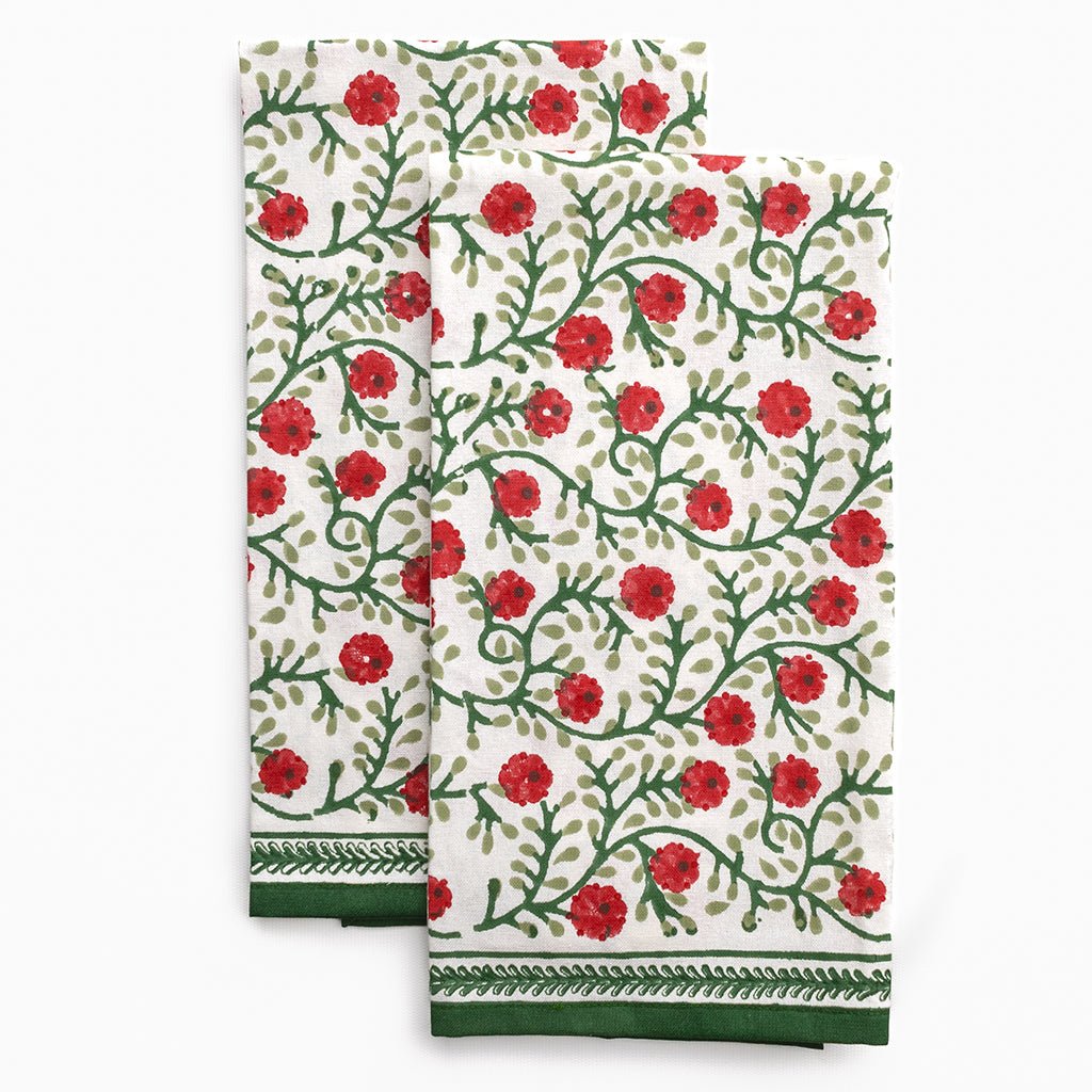 Two floral patterned towels with red flowers and green leaves on a white background