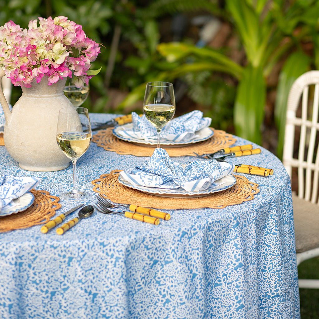 Elegant outdoor table setting with floral centerpiece and patterned tablecloth.