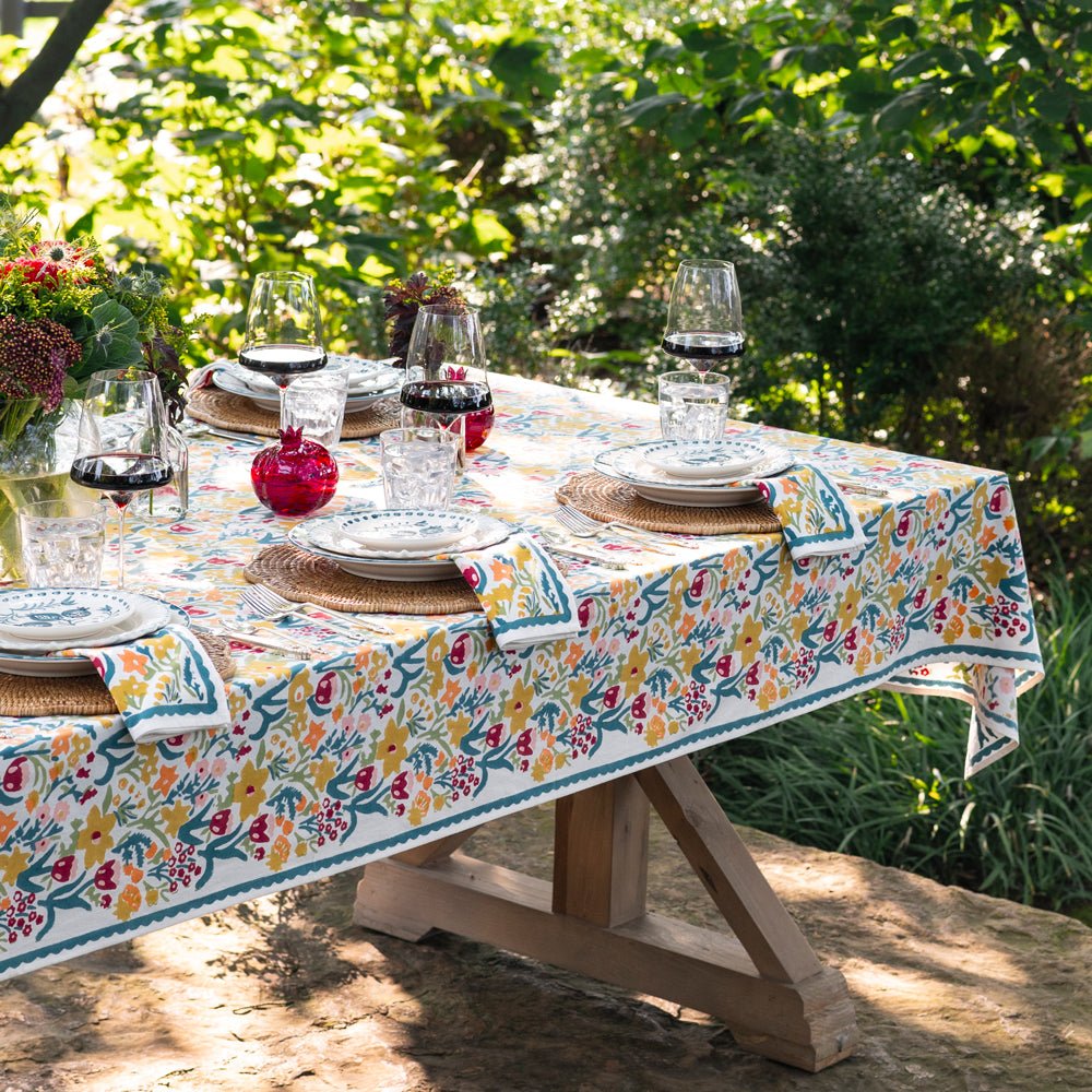 Tablescape set for dinner in a garden with teal and yellow tablecloth