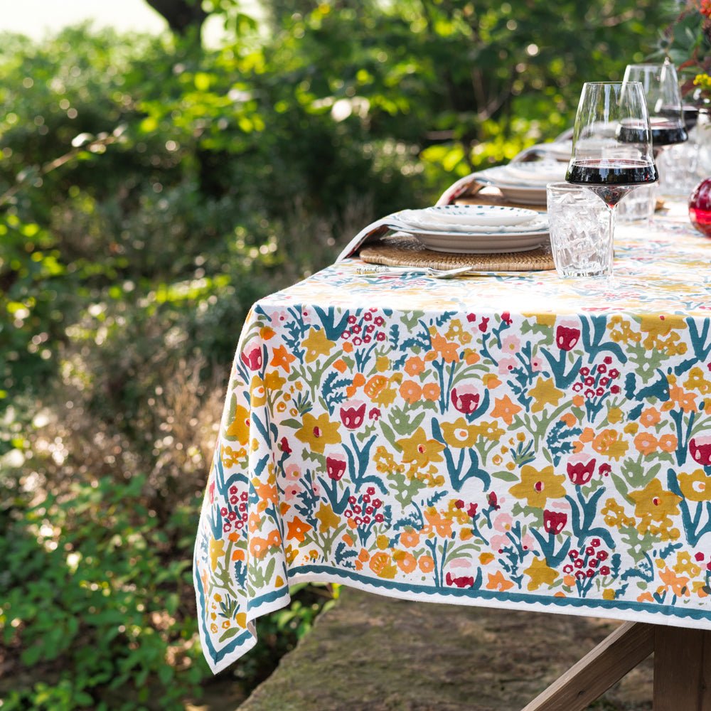 Teal and yellow tablecloth set for dinner in a garden