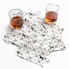 Two glasses of amber liquid on a set of coasters with horses and text printed on them.