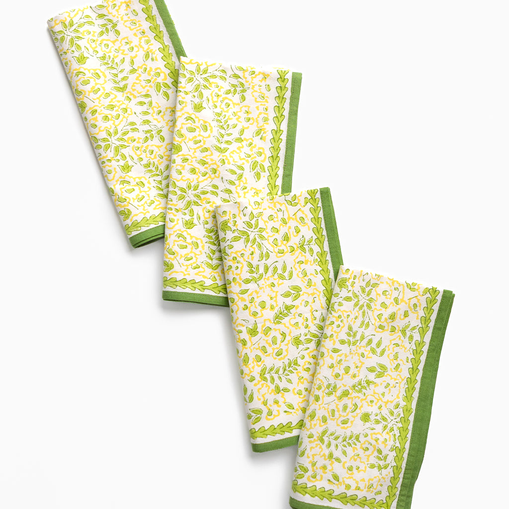 Set of four green and white patterned napkins on a white background