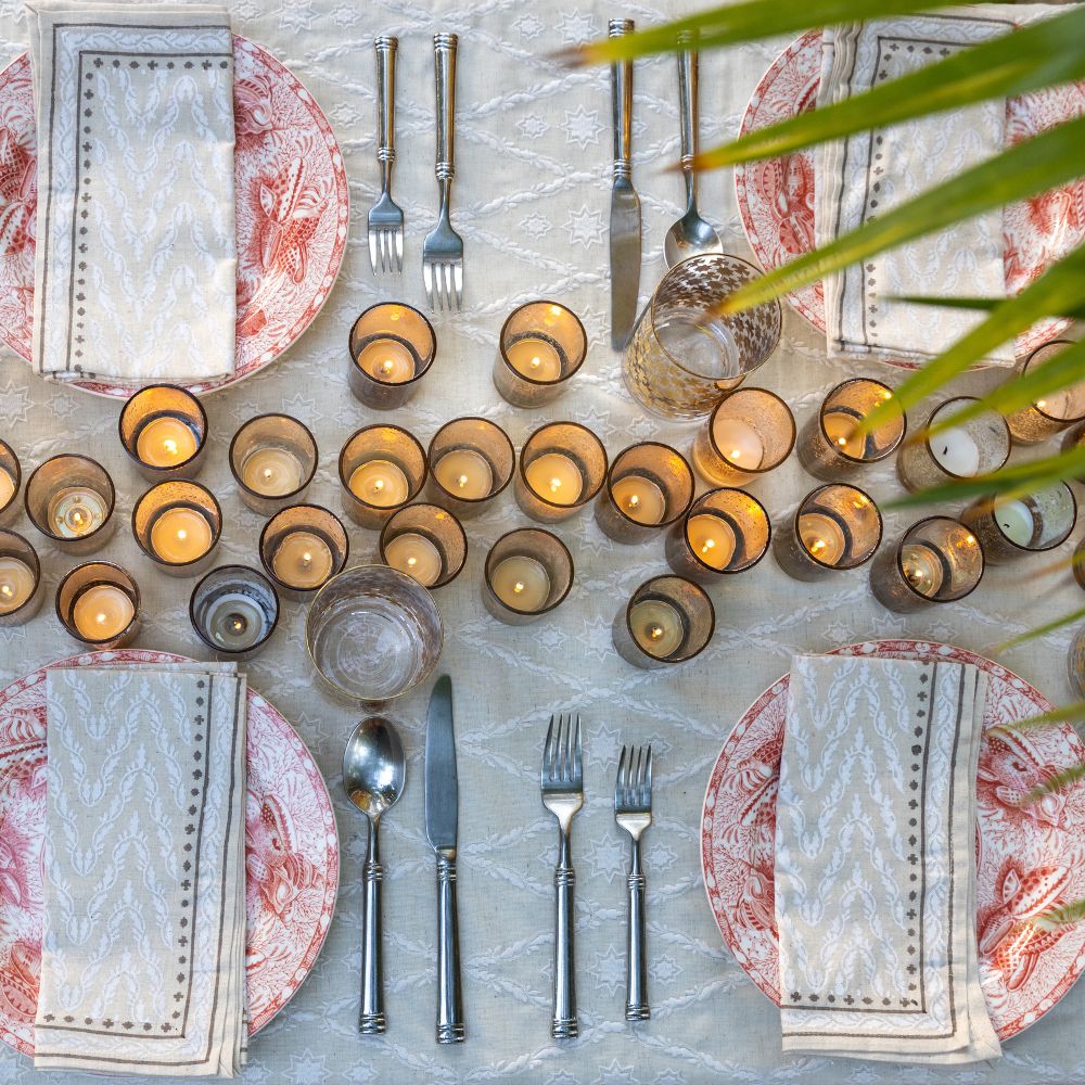 An ivory tablecloth with an embroidered diamond pattern on a dining table set