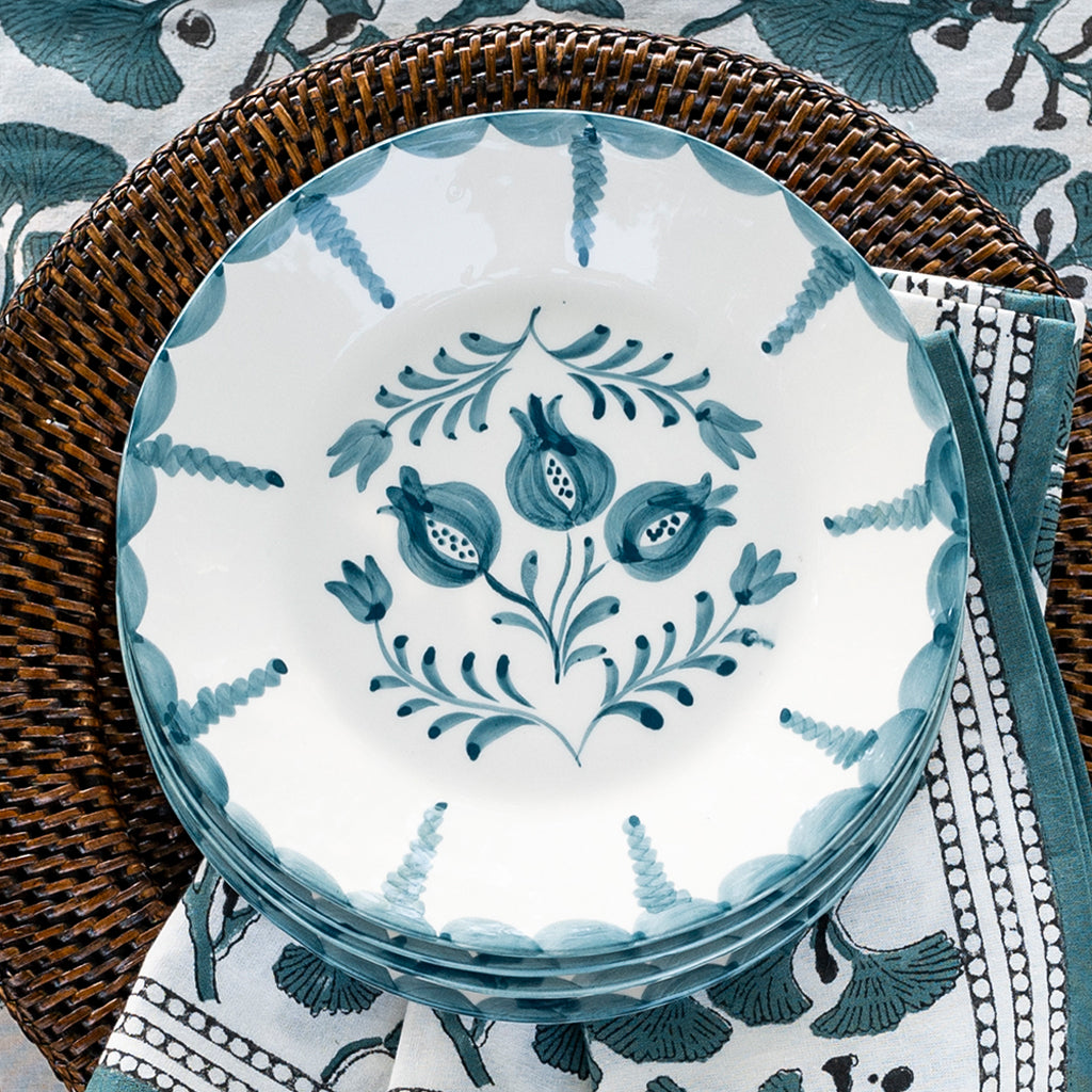 Decorative ceramic plate with blue floral pattern on a woven placemat and patterned cloth.