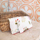 Floral linen cocktail napkin draped over a wicker basket.