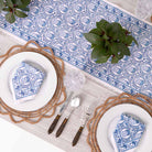 Table runner paired with matching napkin set on dinner table with greenery.