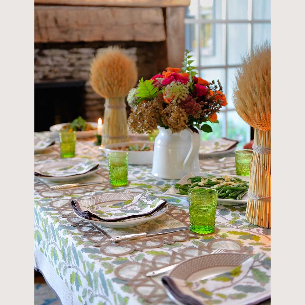 Florals and green glasses on tablecloth. 