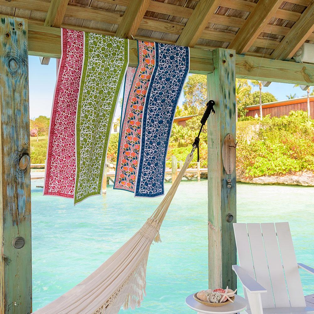 Jewel Blossom table runner draped over wooden beam hanging over body of water. 