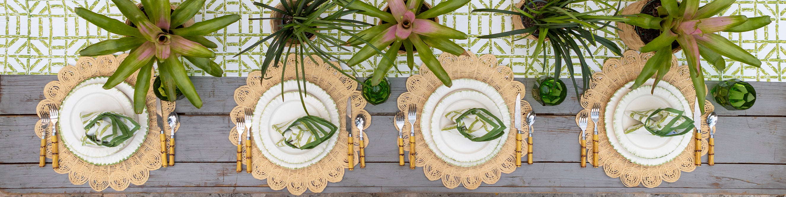 Overhead table setting with four place settings with green and natural accessories.