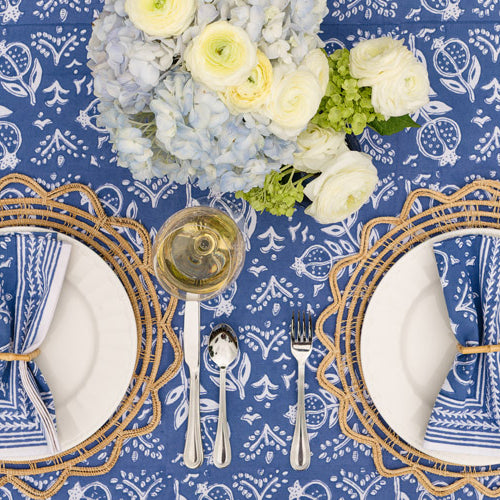 pomegranate blue napkins on white plate with wicker chargers and bamboo napkin rings