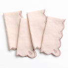 Set of four pink napkins with scalloped edges on a white background
