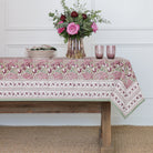 Tablecloth with floral pattern on a wooden table against a white wall.