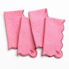 Set of four pink napkins with scalloped edges on a white background