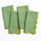 Set of four green napkins with yellow trim on a white background