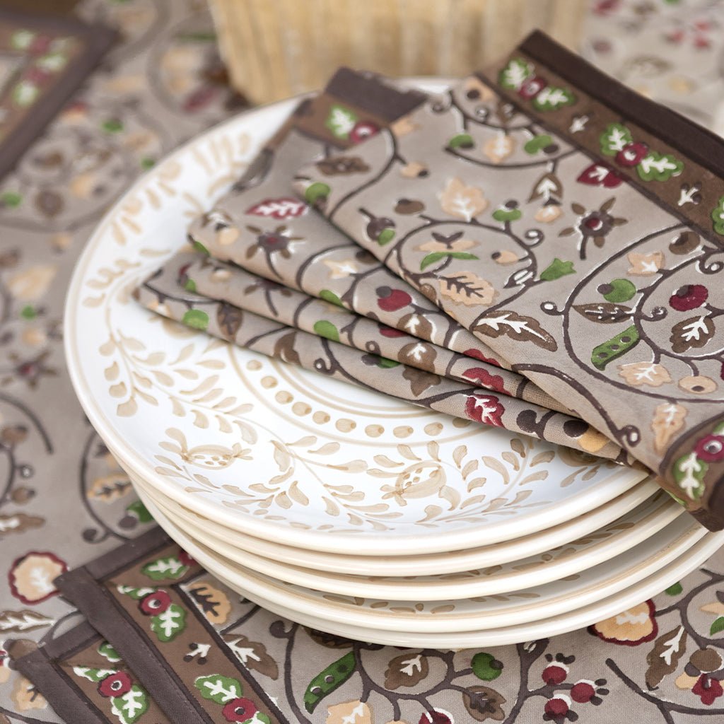 Stack of plates with patterned napkins on a matching tablecloth.