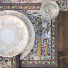Decorative table setting with floral plates, cutlery, and a patterned placemat.