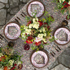 Decorative table setting with patterned plates, flowers, and cutlery on a textured surface.