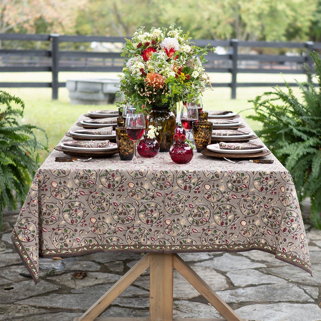 Dining table set with floral centerpiece, plates, and glasses outdoors on a stone patio.