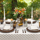 Elegant outdoor table setting with floral centerpieces and patterned tablecloth.