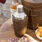 Rattan cocktail shaker on a wood table.