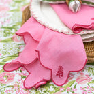 Pink scalloped napkin with a pomegranate embroidery on a floral tablecloth