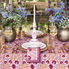 Elegant dining table setting with floral centerpieces, candles, and patterned tablecloth.