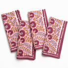 Set of four pink floral patterned napkins on a white background