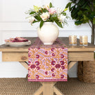 Table with a floral arrangement, candles, and a patterned table runner.