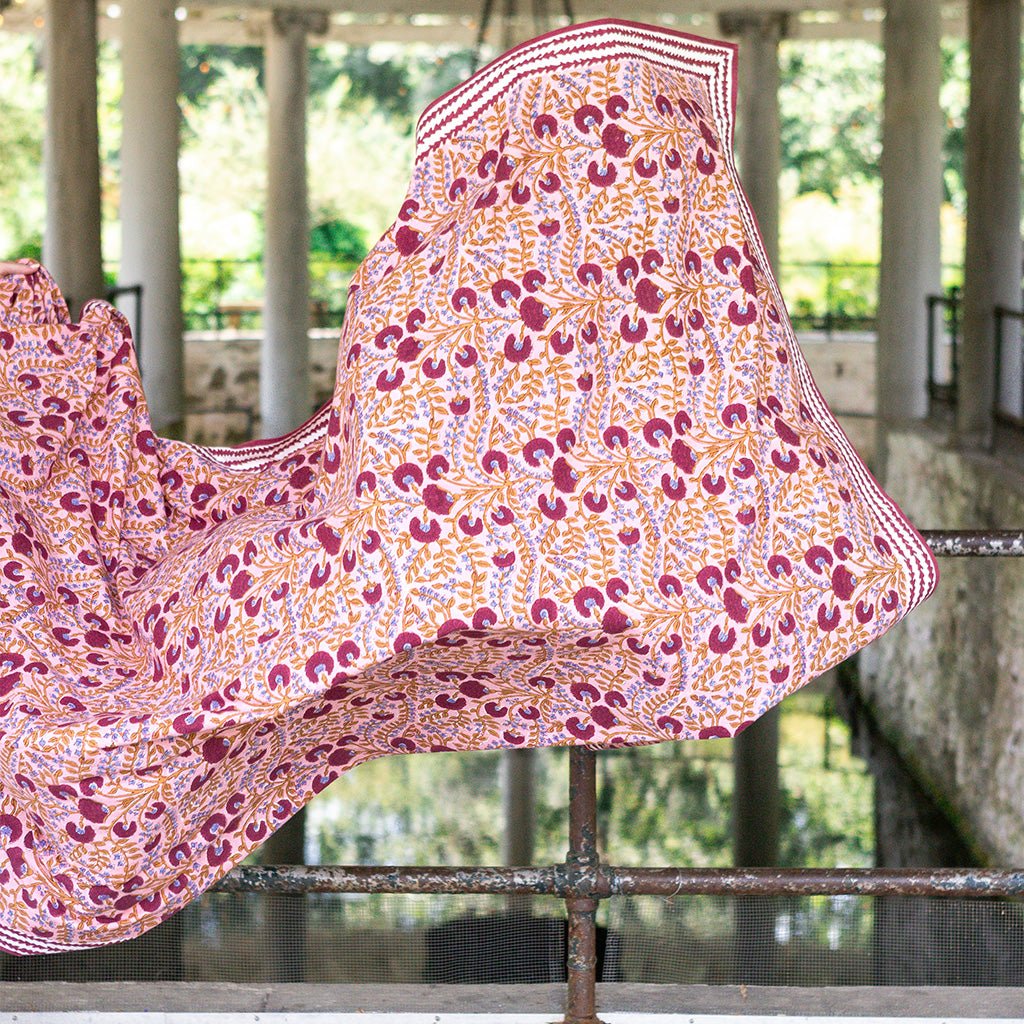 Floral patterned fabric draped over a railing with a blurred natural background