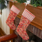 Two floral-patterned Christmas stockings hanging by a fireplace.