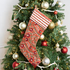 Decorative red Christmas stocking hanging on a Christmas tree with ornaments.